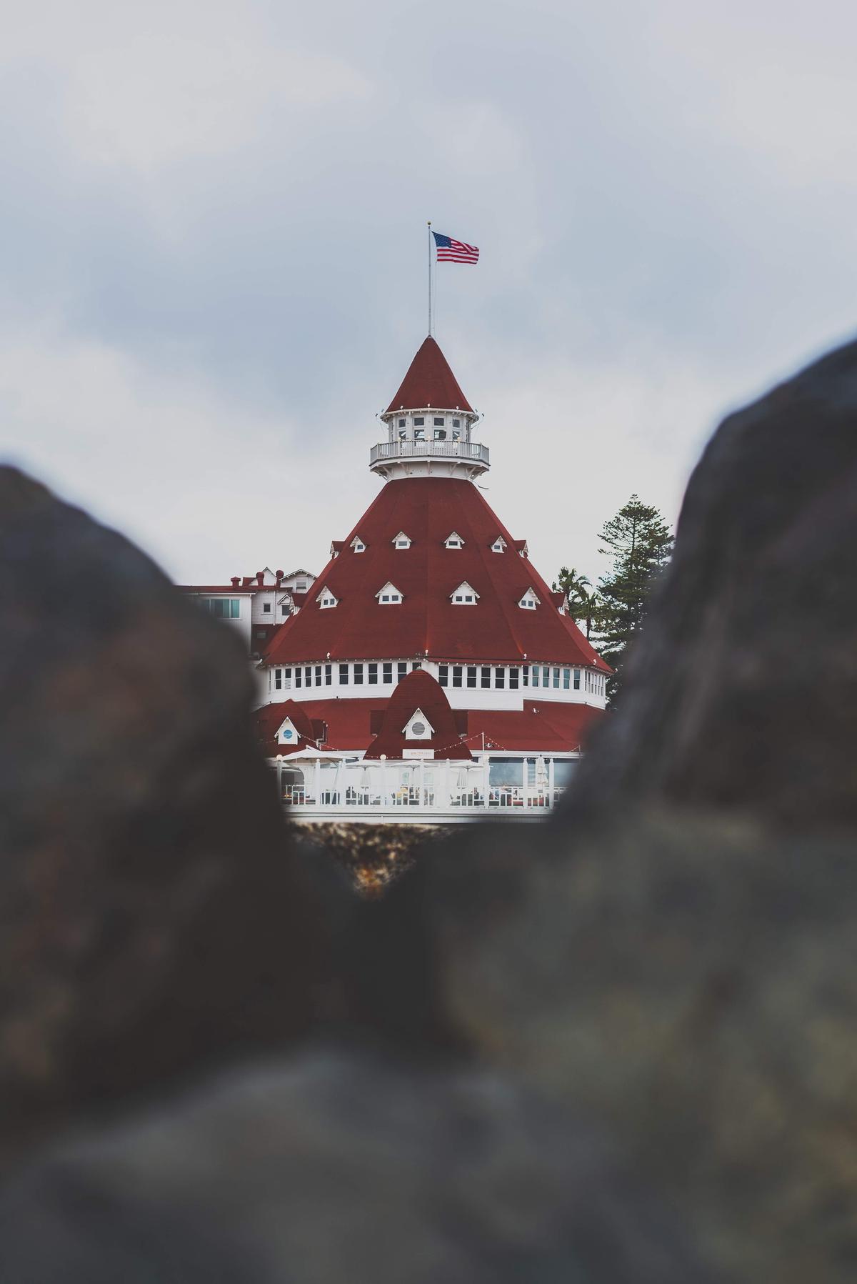 A family is enjoying the sun, sand, and waves on a wide and open beach. The beach's gentle waves provide a safe and enjoyable swimming experience for all. The iconic Hotel del Coronado sits in the background, offering a glimpse of Victorian splendor.