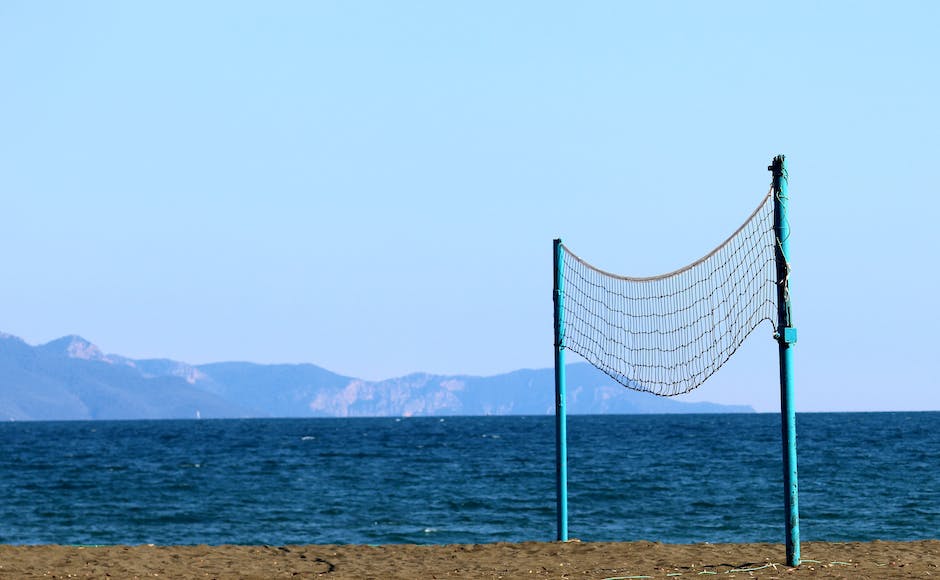 A picture of a beach with a wide stretch of sand, volleyball nets, and the Pacific Ocean in the background.