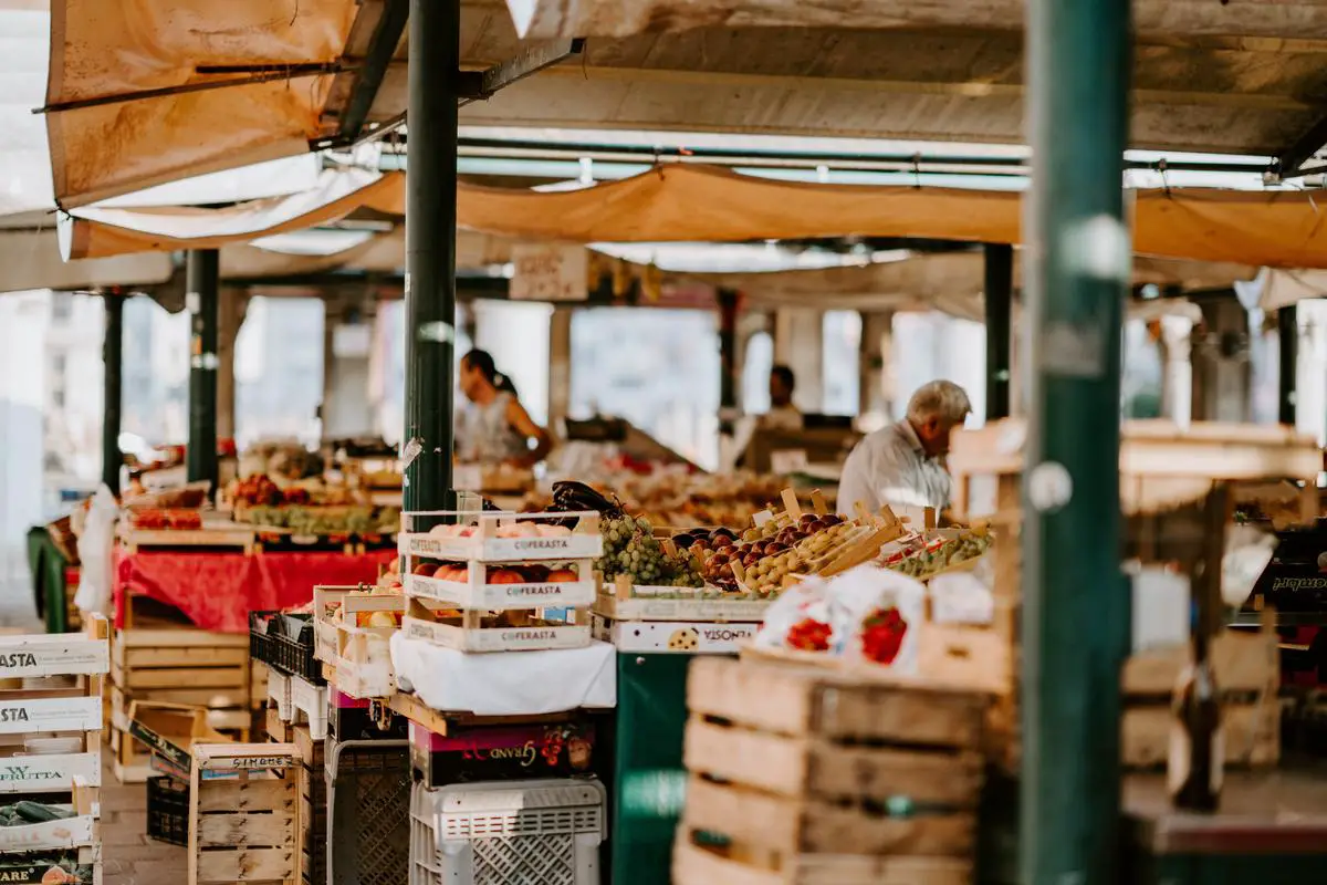 A bustling farmer's market with colorful fruits and vegetables, local crafts, and food stalls serving various cuisines.