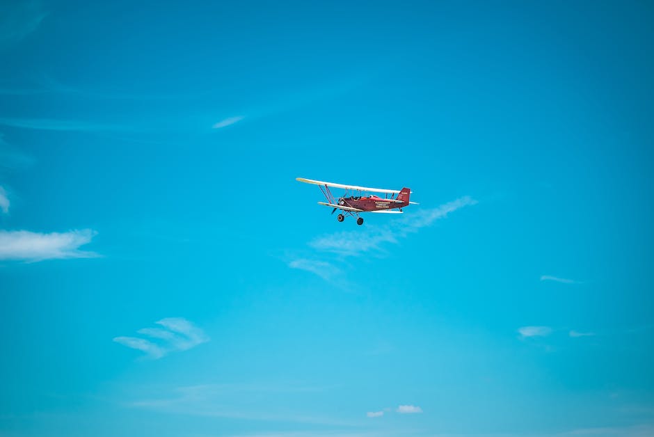 A picture of a person soaring high above the cliffs of the Torrey Pines Gliderport on a glider in the sunny and clear skies of San Diego.